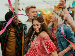 Group of people dancing joyfully at a festive outdoor event with colorful decorations
