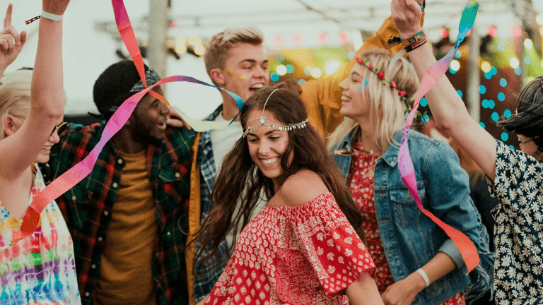 Group of people dancing joyfully at a festive outdoor event with colorful decorations